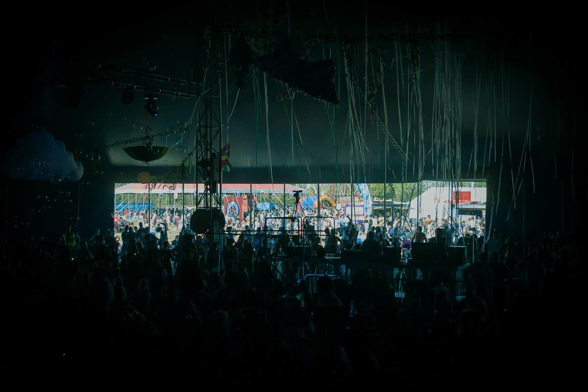 Energetic festival crowd under bright colourful stage lighting at an outdoor summer event