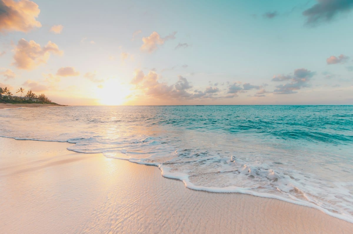 Tropical beach with clear turquoise water and white sand under bright sunshine