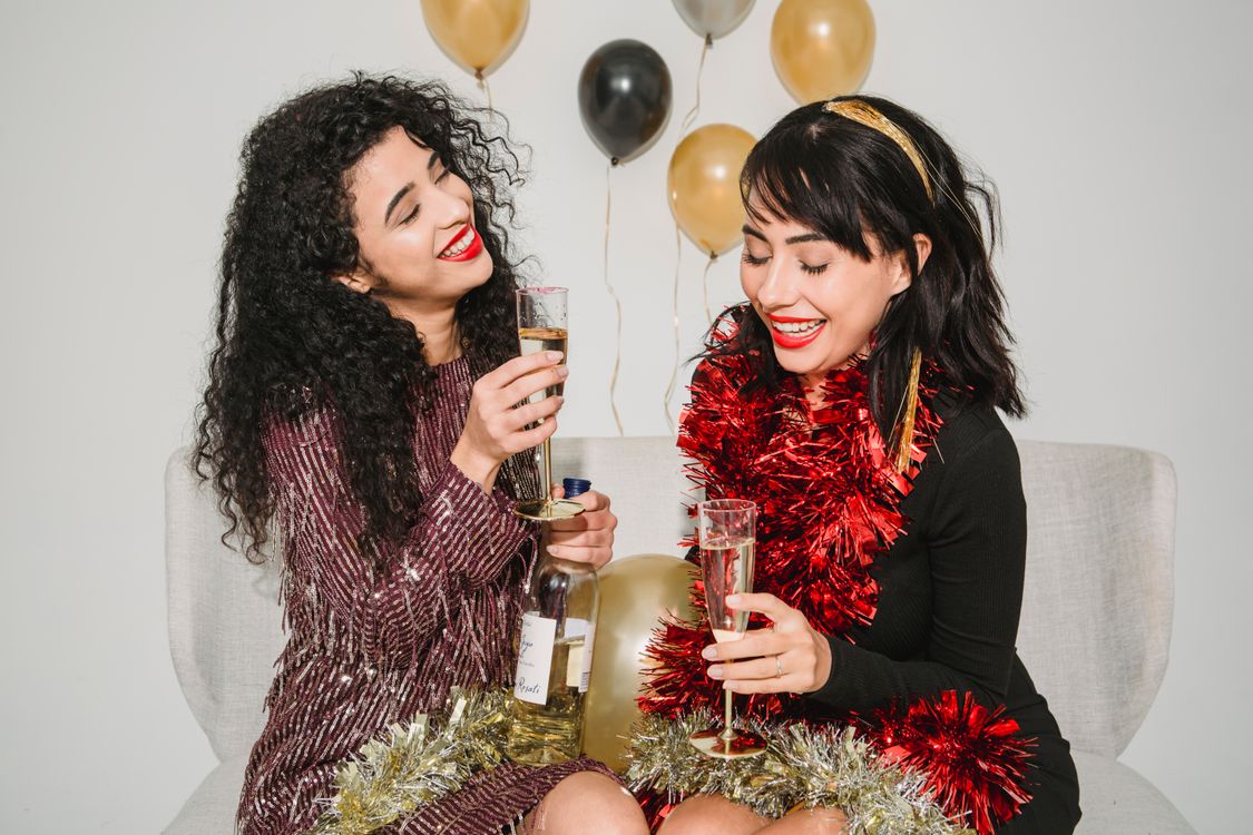 Cheerful women celebrating with champagne among colourful balloons at a party